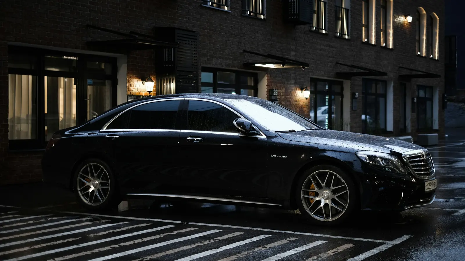Black Mercedes-Benz S-Class parked outside a hotel at night